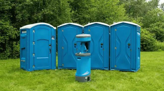 Four blue portable toilets and a matching hand washing station on grass near trees, a common sight at local outdoor events in Lakeland, FL