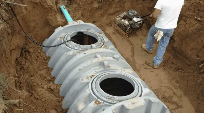 Septic tank installation showing a technician compacting soil around a new poly septic tank in an excavation pit in Lakeland, FL